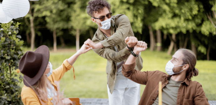 Tres personas con mascarillas saludándose con el puño